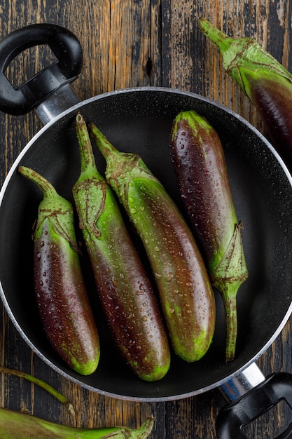 Unripe eggplants in a pan on a wooden.