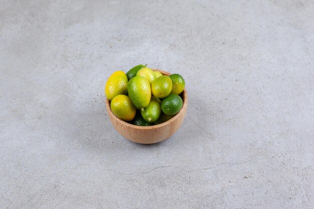 Unripe kumquats piled in a bowl on marble surface