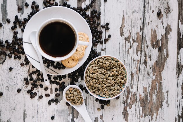 Unroasted coffee beans near cup of coffee