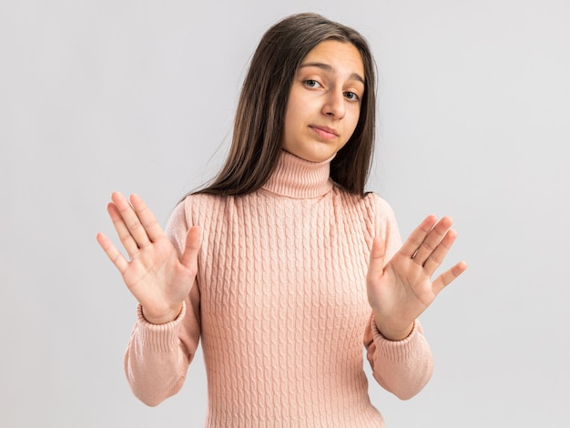 白い壁に隔離された拒否ジェスチャーをしている不満のかわいい10代の少女