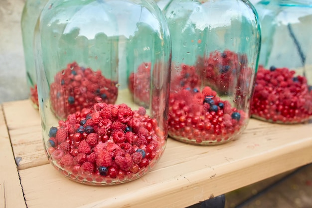 Free photo unsealed glass jars with raspberries and currants prepared for canning