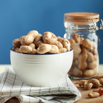 Неочищенный арахис в миске на кухонном полотенце концепция здорового питания закуска для вегетарианцев ...