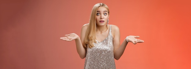 Free photo unsure clueless awkward attractive blond european woman in silver glamour dress shrugging hands