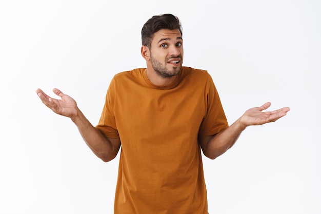 Unsure clueless cute boyfriend cant answer, dont know what do, standing puzzled and troubled say something, standing white background, shrugging spread hands sideways indecisive