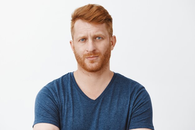 Unsure displeased redhead mature male entrepreneur looking suspiciously with raised eyebrows and serious face, unimpressed or showing disbelief