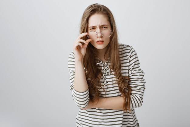 Unsure girl with bad vision, squinting and looking with glasses