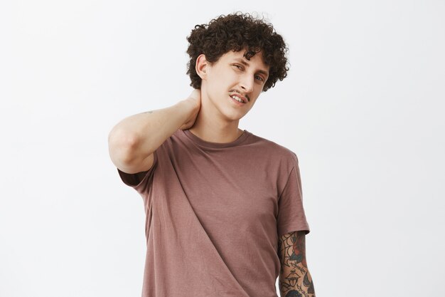 unsure handsome and stylish curly-haired guy with displeased unhappy and lazy expression
