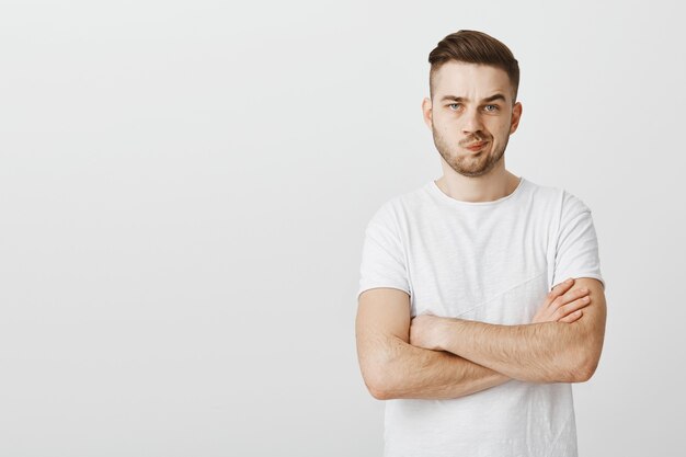 Unsure young man cross arms chest and looking doubtful, making decision