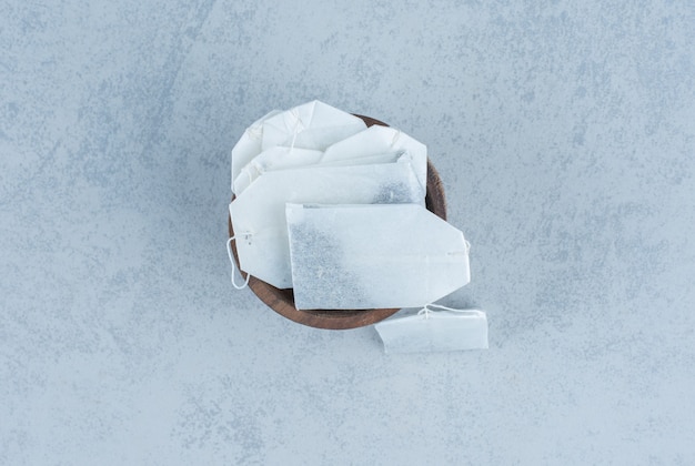 Unused tea bags in a bowl on marble.