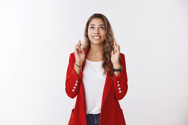 Upbeat excited charming optimistic cute female wearing red jacket praying looking skies cross fingers good luck anticiapting good news smiling broadly hopefully dreaming wish come true