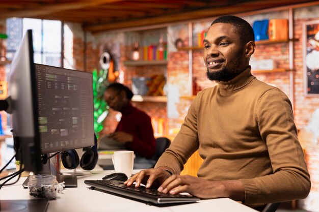 スタートアップのオフィスで高度なAIアルゴリズムをコードする楽観的なITエンジニア