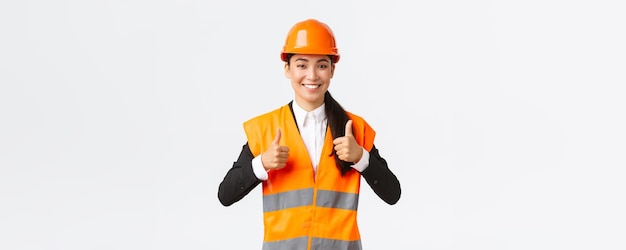 Upbeat pleased asian female architect giving permission proud with result standing in safety helmet