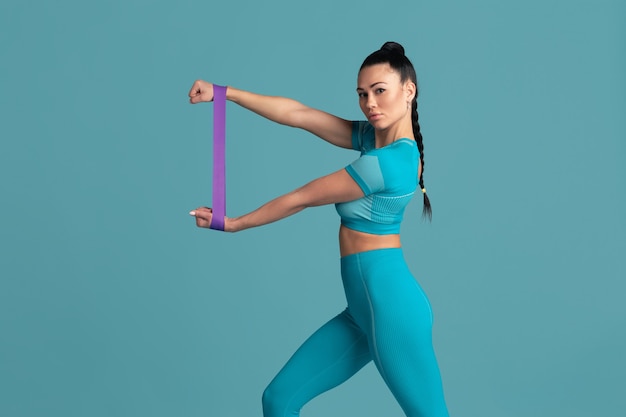 Upper body. Beautiful young female athlete practicing in studio, monochrome blue portrait