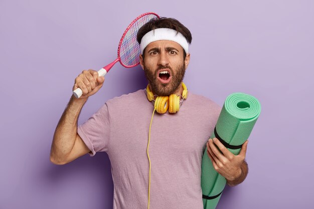 Upset active man posing with sports equipment