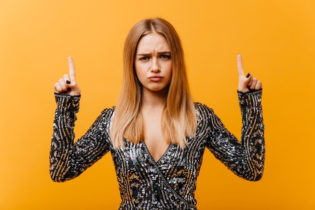 Foto gratuita donna incredibile sconvolta in abbigliamento da festa in posa con le mani in alto. ritratto di donna piuttosto bionda.