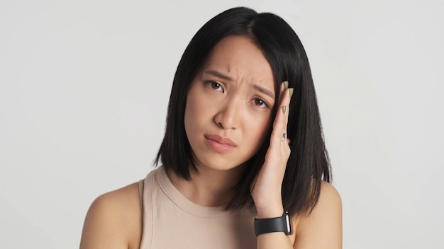 Free photo upset asian woman looking guilty at camera over white background sad expression