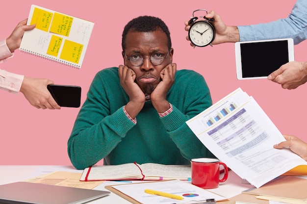 Upset black male worker has much work, thinks about business project, being lack of time