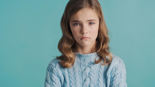 Free photo upset blond teenage girl feeling sad because of bad marks at school posing isolated on blue background. offended girl