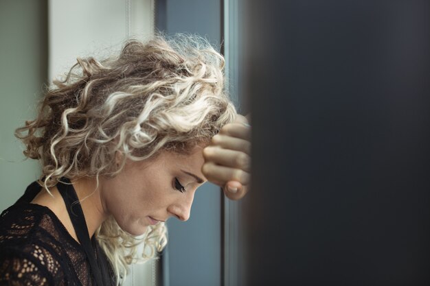 Upset businesswoman leaning on window