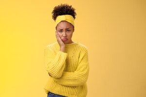 Upset cute gloomy young timid girl offended feel sadness regret touch cheek painful toothache make upset miserable pitty expression, troubled uncertain what do standing insecure yellow background.