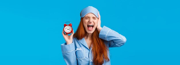 Upset and distressed screaming redhead lovely girl feeling bothered and depressed holding red alarm 