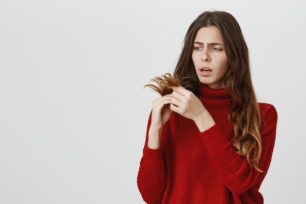 Upset girl looking at split ends