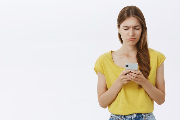 悲しいスマートフォンの画面を見ている動揺の暗い女の子