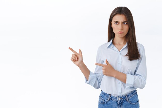 Upset or jealous cute brunette woman in blouse pouting, sulking with regret, being offended not invited to cool office party