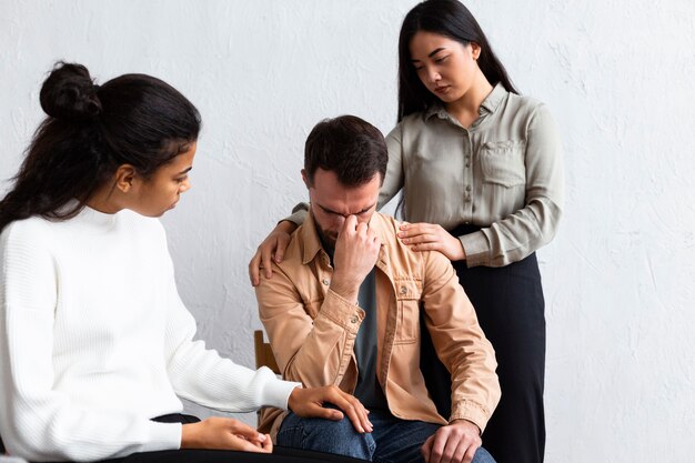 Upset man being consoled at a group therapy session