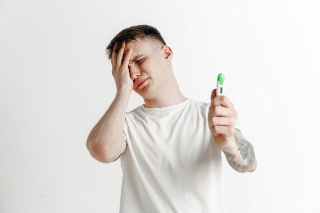 Upset man looking in pregnancy test. Human emotions concept