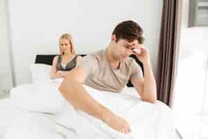 Free photo upset man sitting with his sad woman in bed at home