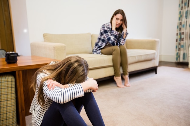 Upset mother and daughter sitting in living room