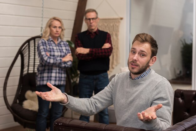 Upset parents looking at son on sofa