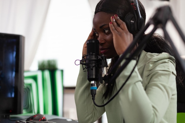 Upset sad pro gamer playing space shooter video games using RGB computer, gaming for online championship. Nervous woman player with headphones talking with remote player using live streaming