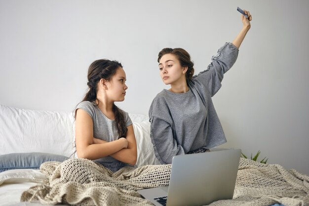 Upset teenage girl crossing arms on chest, being angry at mother who is taking away credit card