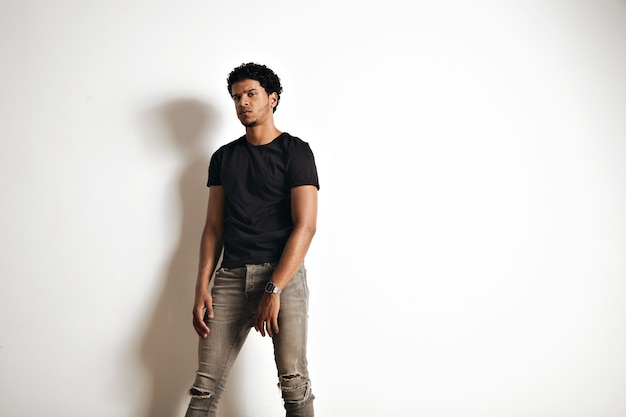 Upset tired muscular black young man in an unlabeled cotton t-shirt and skinny jeans isolated on white