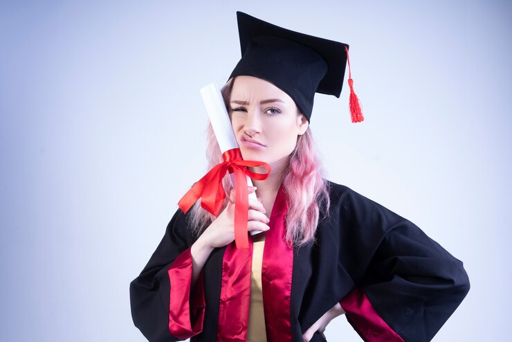 Free Photo upset woman in a bachelor cap and mantle holds her graduation certificate