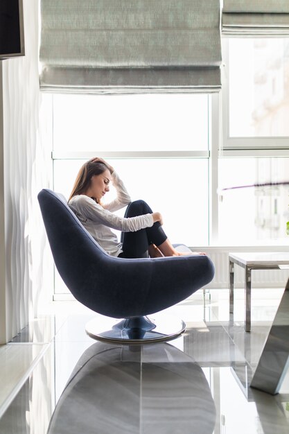 Upset woman cry covering her face by hand. Concept of young girl depression, stress and problems, pain, female depressed sitting in chair close up face with hands