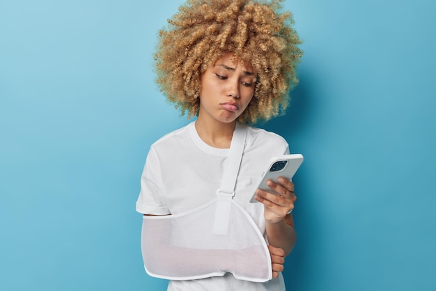 화가 난 여성은 팔이 부러져 채팅을 위해 휴대전화를 사용하고 있다