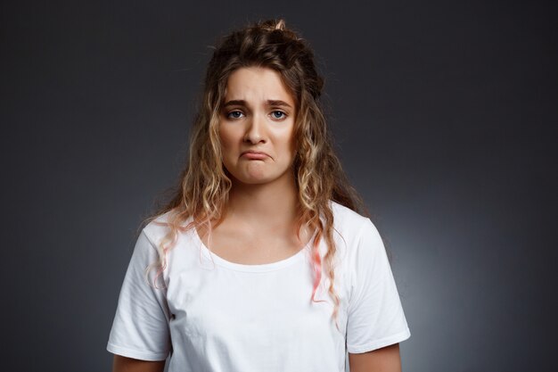  upset young beautiful girl over grey wall.