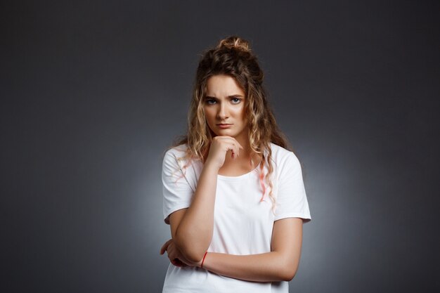  upset young beautiful girl over grey wall.