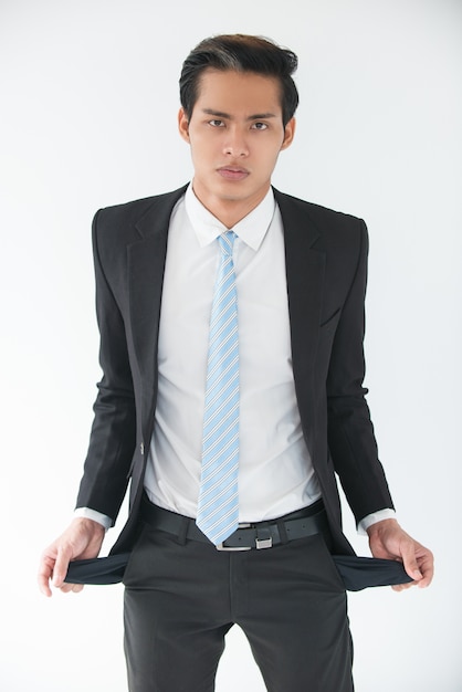 Free photo upset young businessman showing empty pockets