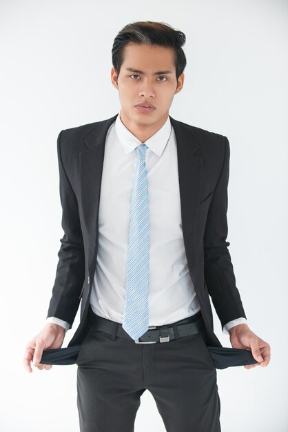 Upset young businessman showing empty pockets