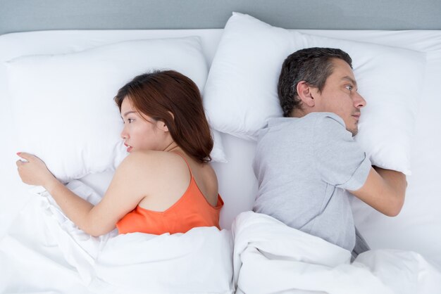 Upset Young Couple Lying in Bed Back to Back
