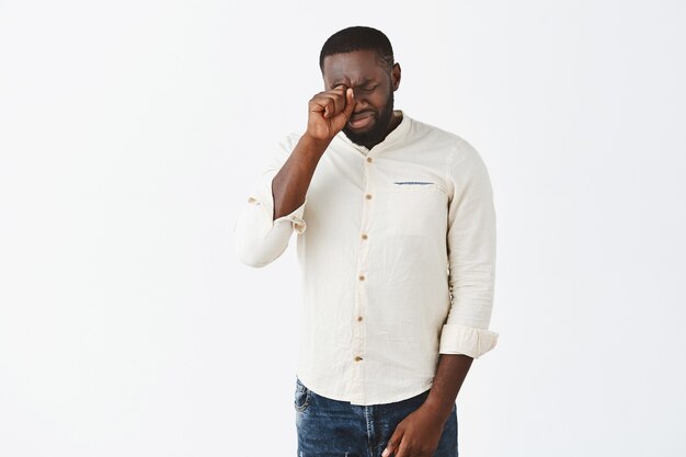 Upset young guy posing against the white wall