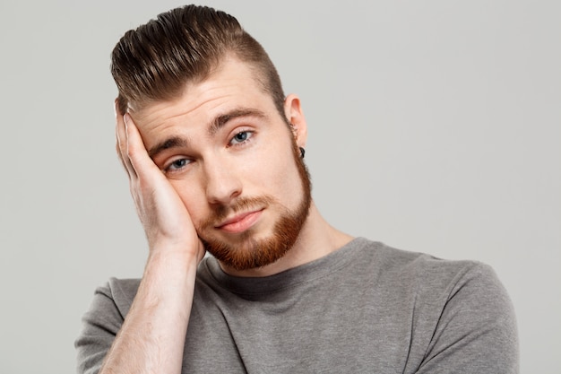 Upset young handsome man posing over grey wall.