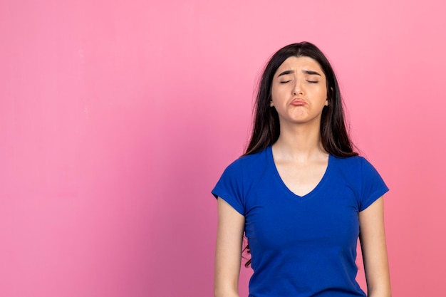 An upset young lady standing on pink background High quality photo