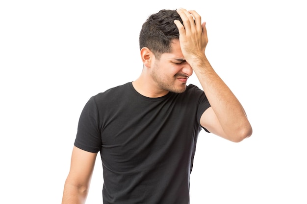 Upset young man suffering from headache against white background
