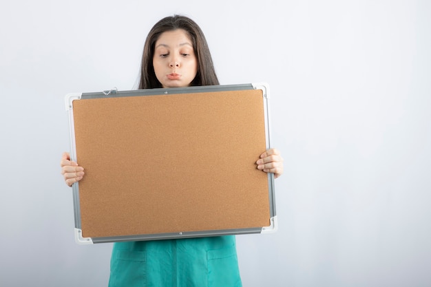 Free photo upset young woman holding board and looking on it.