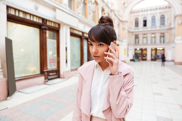 Upset young woman receiving bad news while talking on mobile phone